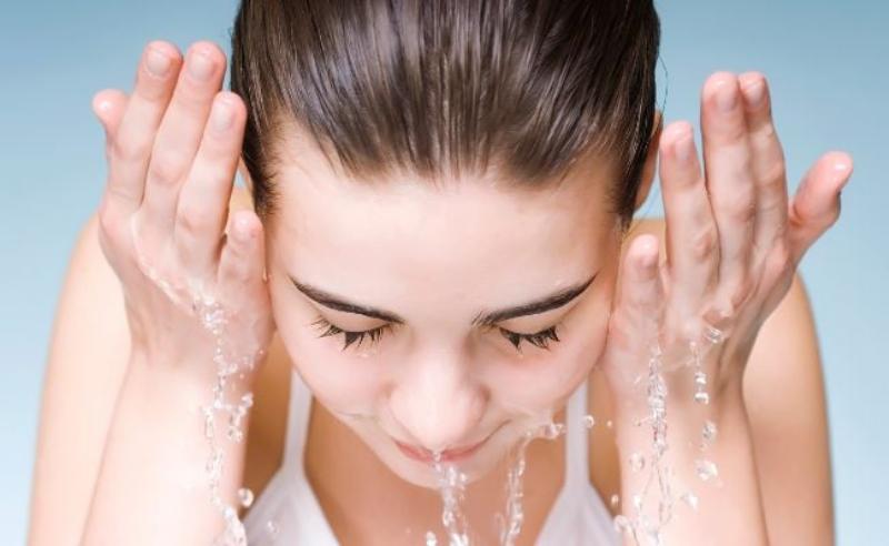 Một người phụ nữ đang nhẹ nhàng vỗ lên mặt sau khi gỡ mặt nạ giấy, minh họa bước massage để tinh chất thẩm thấu