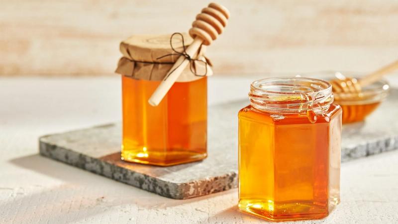 Giọt nước giặt màu xanh hoặc hồng đậm đặc nhỏ xuống từ nắp chai vào một chậu nước, tạo ra nhiều bọt, minh họa cho tính đậm đặc và khả năng tạo bọt tốt của sản phẩm.