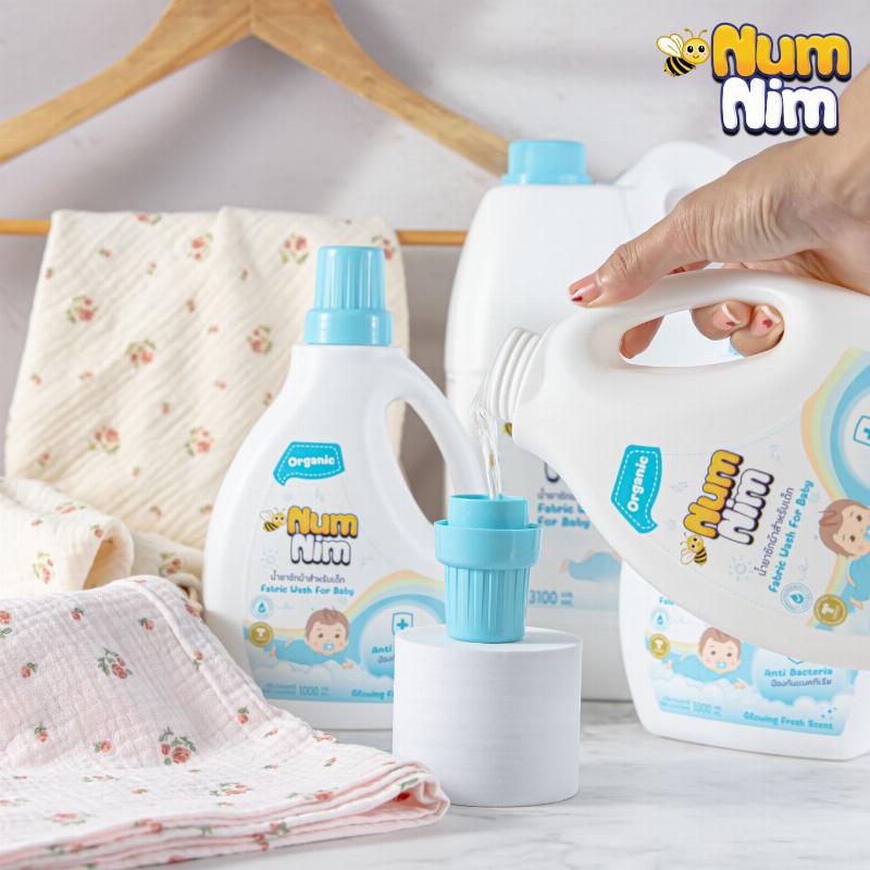 Hình ảnh một chai nước giặt Thái Lan có nhãn "Thân Thiện Môi Trường" hoặc "Phân Hủy Sinh Học", phông nền là cây xanh và dòng nước sạch, tượng trưng cho sự an toàn và bền vững.