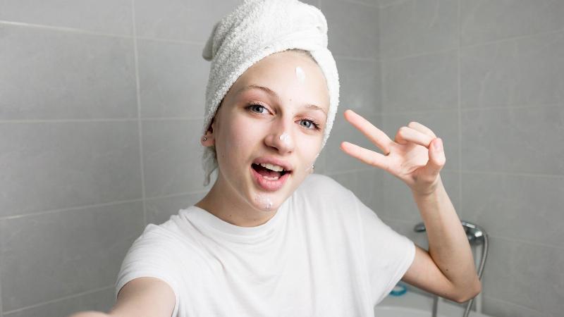 Simple sữa rửa mặt được đặt cạnh bông tẩy trang và một nhánh hoa nhỏ, gợi cảm giác dịu nhẹ, tự nhiên.